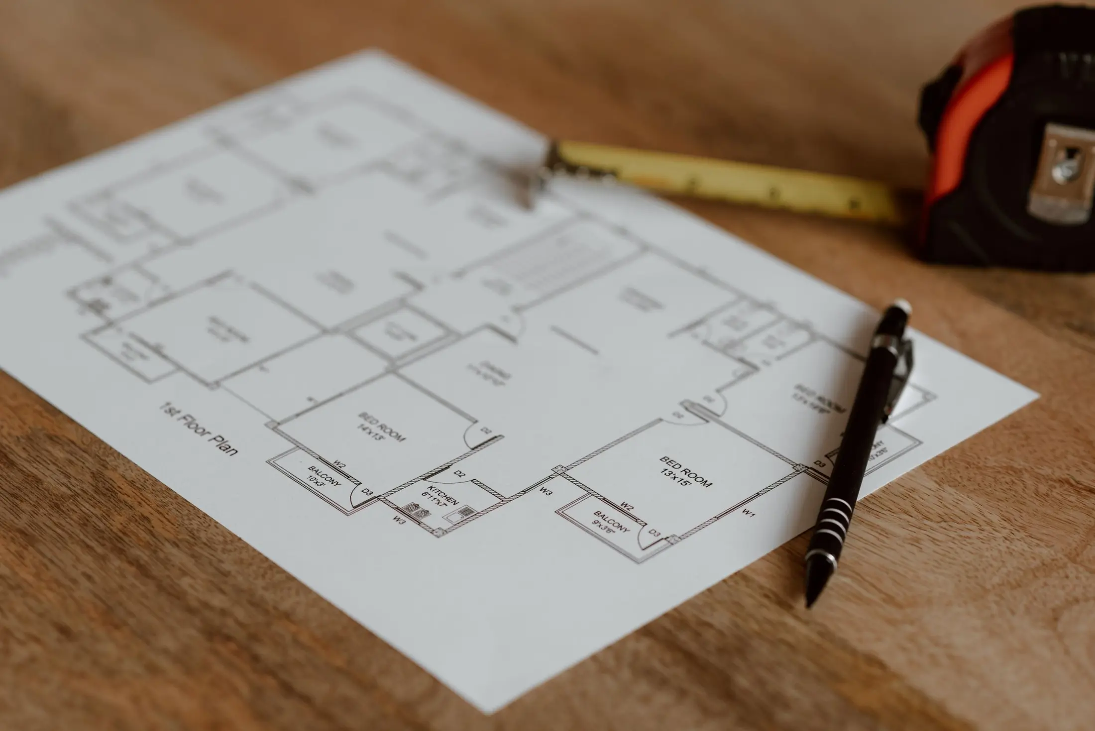 Grundriss, Maßband und Stift auf einem Holztisch